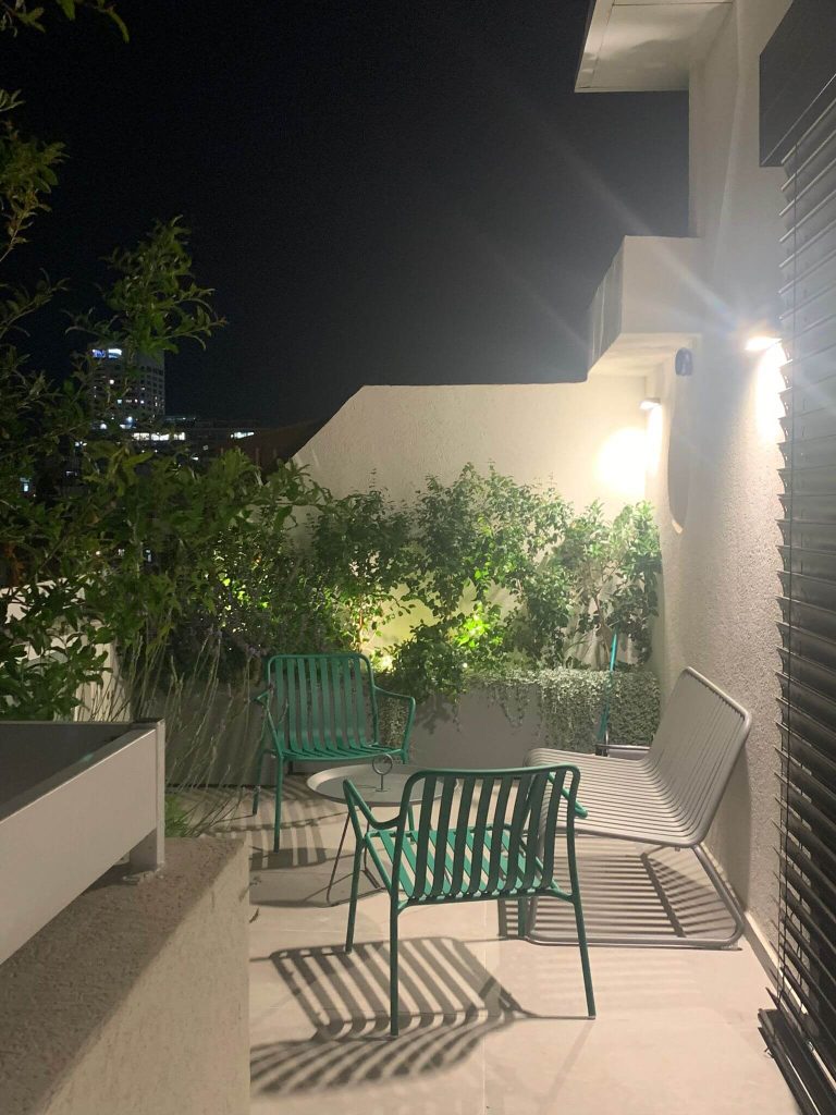 פינת ישיבה על מרפסת מעוצבת עם צמחייה ירוקה - גן בגג